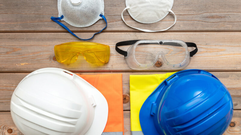 Work safety protection equipment. Industrial protective gear for two on wooden background. Construction site health and safety concept