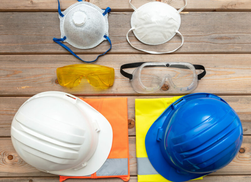 Work safety protection equipment. Industrial protective gear for two on wooden background. Construction site health and safety concept